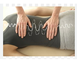 Une patiente avec une scoliose est couchée sur le ventre. Les mains du thérapeutes sont délicatement posées en haut et en bas due son dos
